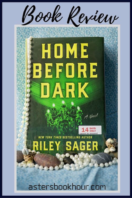The pinterest image for Home Before Dark by Riley Sager book review. There is a blue floral print background with the novel centered in the middle and the cover facing the front. The words book review are in fake cursive over the top.