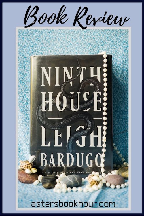 The pinterest image for Ninth House by Leigh Bardugo book review. There is a blue floral print background with the novel centered in the middle and the cover facing the front. The words book review are in fake cursive over the top.