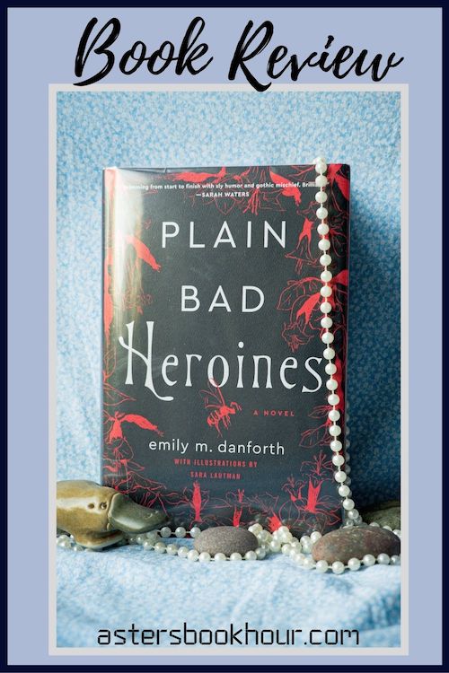 The pinterest image for Plain Bad Heroines by Emily M. Danforth book review. There is a blue floral print background with the novel centered in the middle and the cover facing the front. The words book review are in fake cursive over the top.