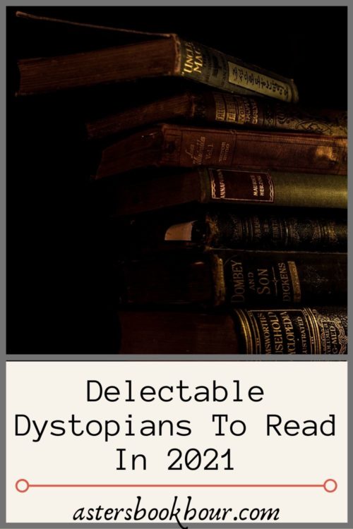 The pinterest image for Delectable Dystopians To Read In 2021. It states the title on the bottom and then above has the same featured image on top. The featured image has 7 antique books stacked haphazardly on top of each other skewing to the left of the frame. They are all dark in nature along with the image as it is quite moody with a black background. Only the seven novels are in focus with lighting predominately on the right side.