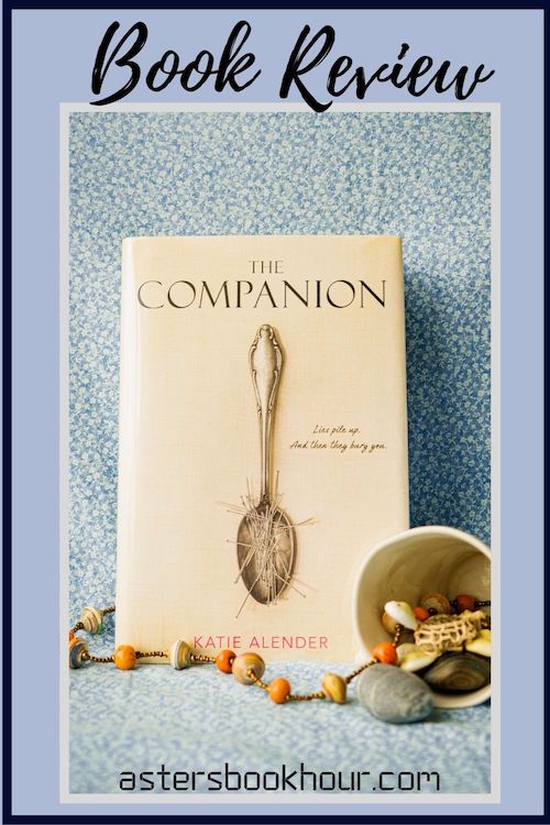 The pinterest image for The Companion by Katie Alender book review. There is a blue floral print background with the novel centered in the middle and the cover facing the front.