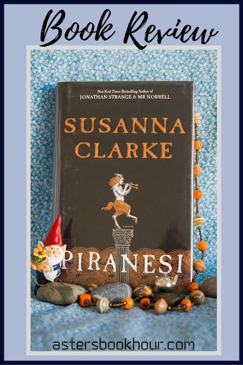 The pinterest image for Piranesi by Susanna Clarke book review. There is a blue floral print background with the novel centered in the middle and the cover facing the front.
