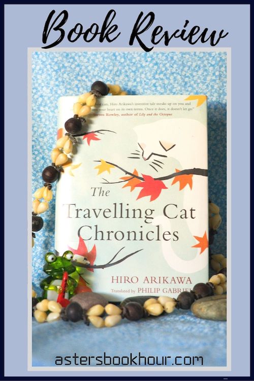 The pinterest image for The Travelling Cat Chronicles by Hiro Arikawa book review. There is a blue floral print background with the novel centered in the middle and the cover facing the front.