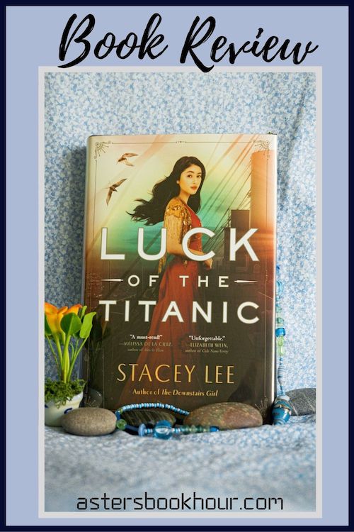 The pinterest image for Luck of the Titanic by Stacey Lee book review. There is a blue floral print background with the novel centered in the middle and the cover facing the front.