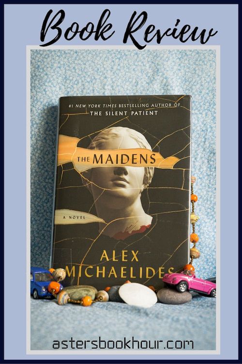 The pinterest image for The Maidens by Alex Michaelides book review. There is a blue floral print background with the novel centered in the middle and the cover facing the front.